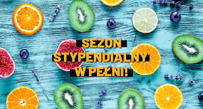 Sezon stypendialny w pełni. Pomarańczowy napis na tle owoców na niebieskim stole
